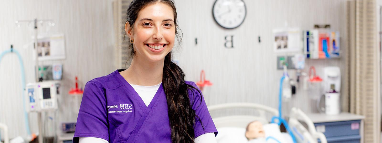 nursing student poses in scrubs