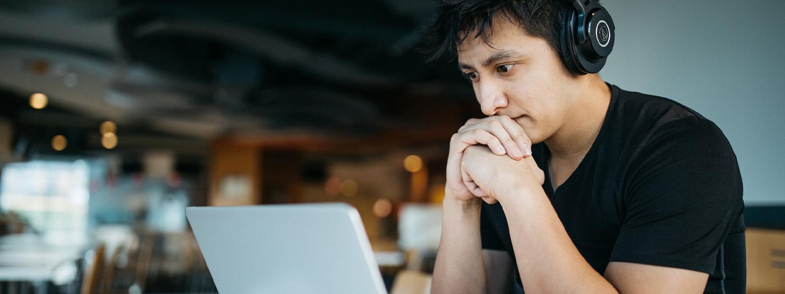 student with headphones working on laptop